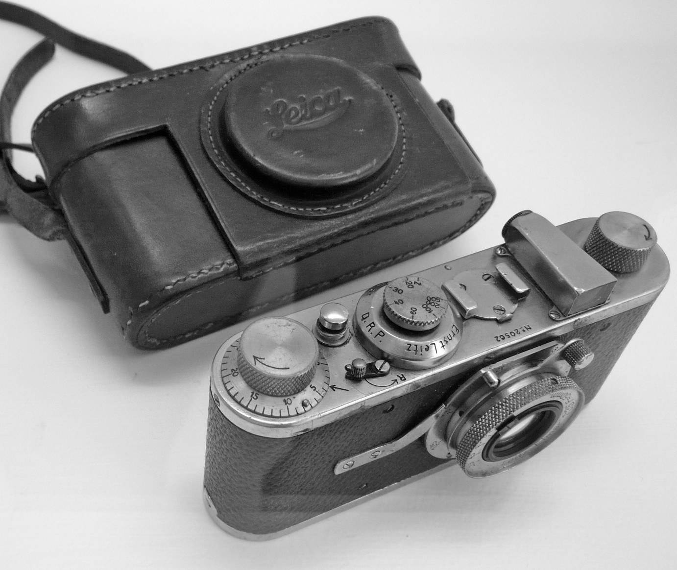 A small early Leica camera beside its worn leather case