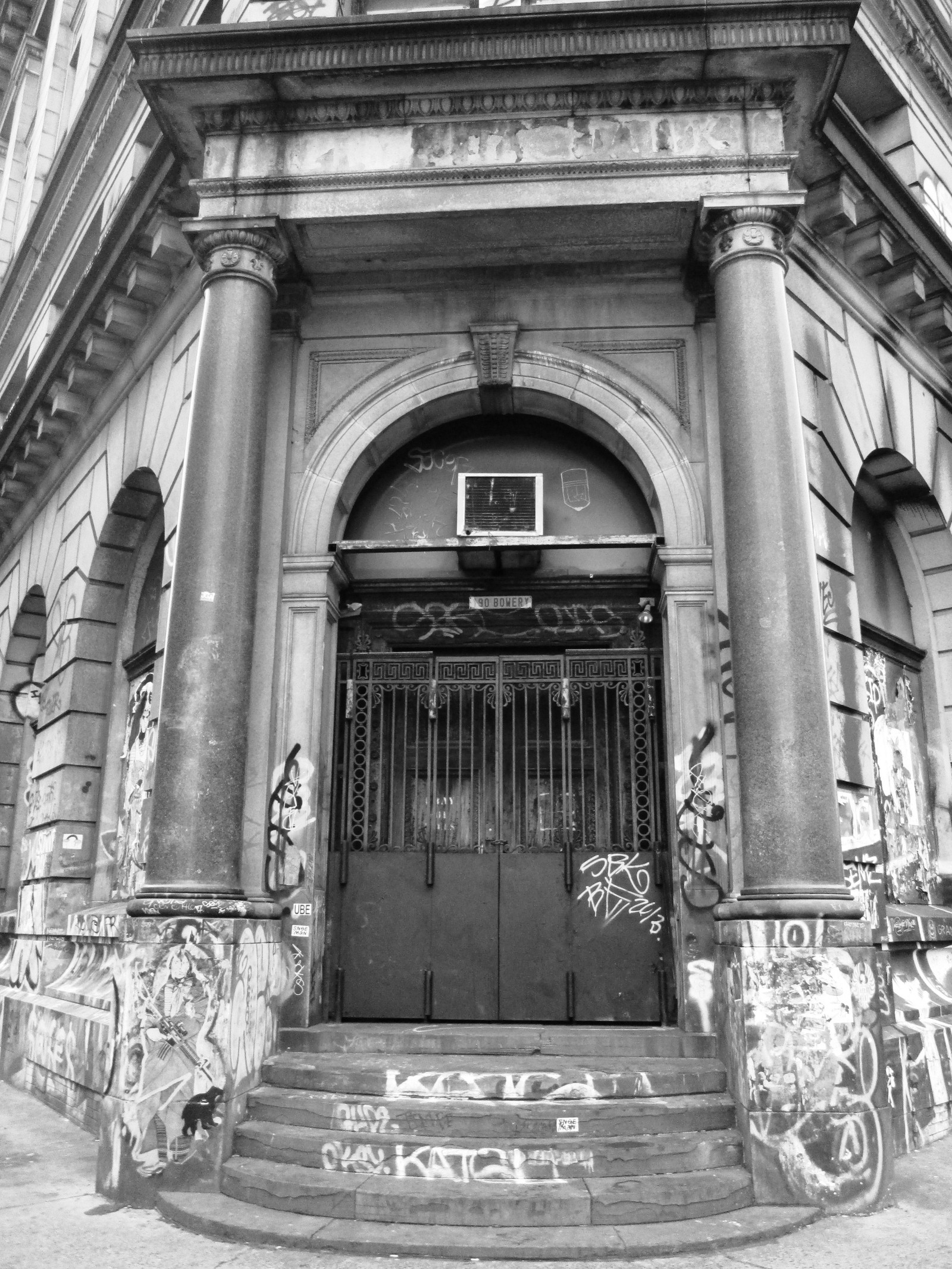 The columned stone entrance of 190 Bowery, covered in graffiti
