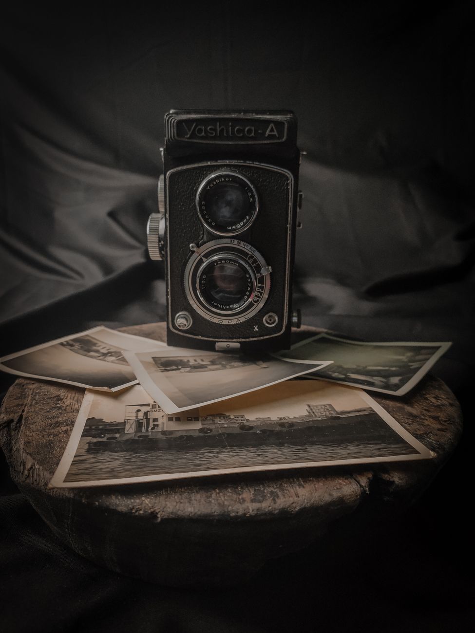 photograph of a vintage camera and pictures on a wooden surface