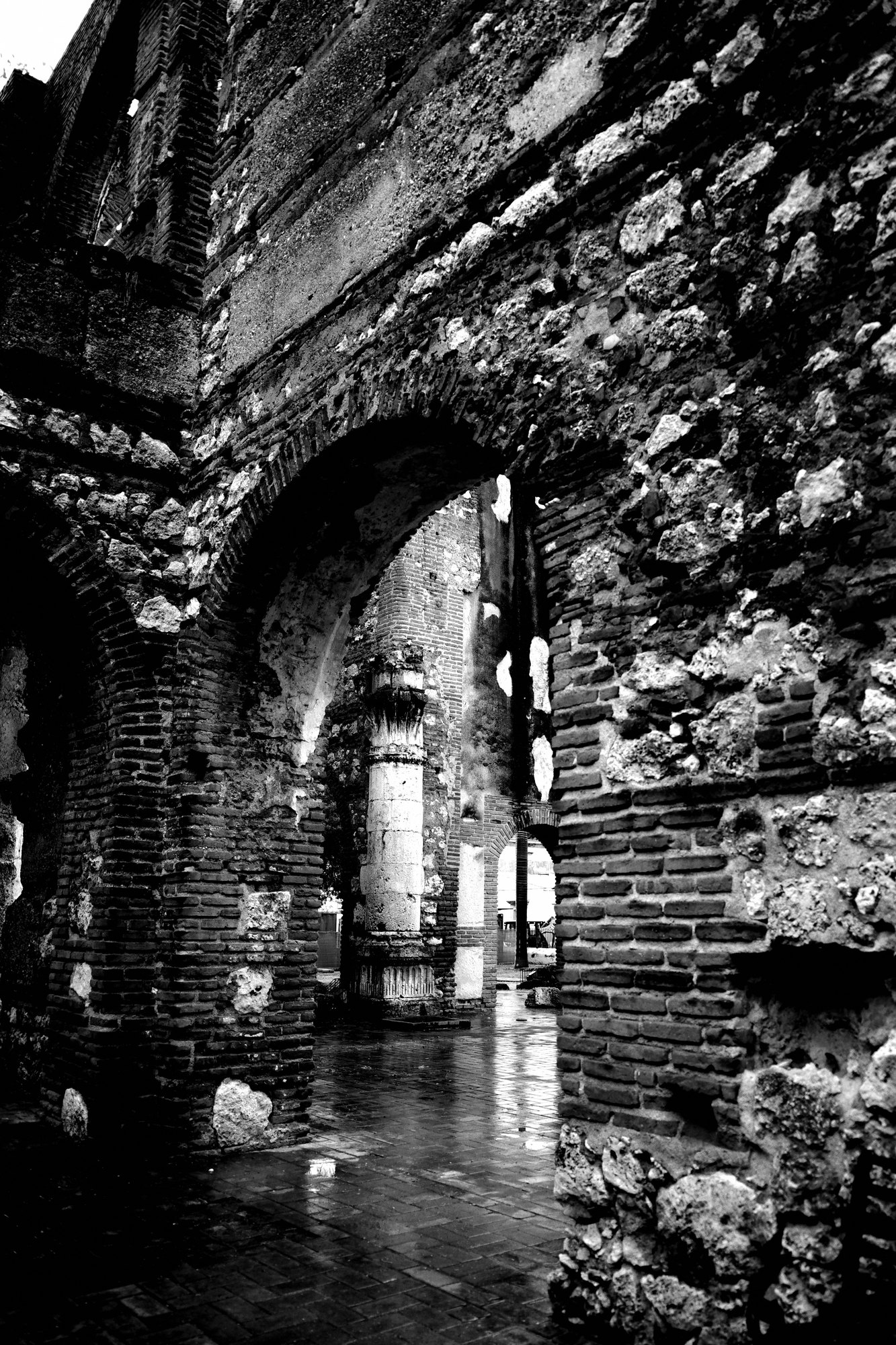Brick arches inside a ruin with water pooled across the floor and daylight coming through the far opening