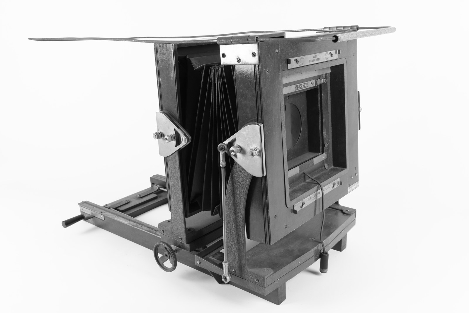 A Deardorff large format studio camera in wood and metal with its bellows extended, seen against a plain background