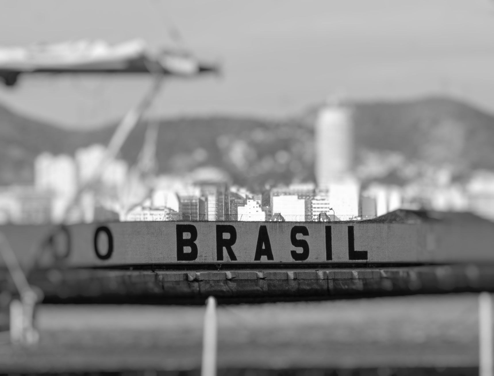 The stern of a navy ship lettered BRASIL with the city and hills soft behind it