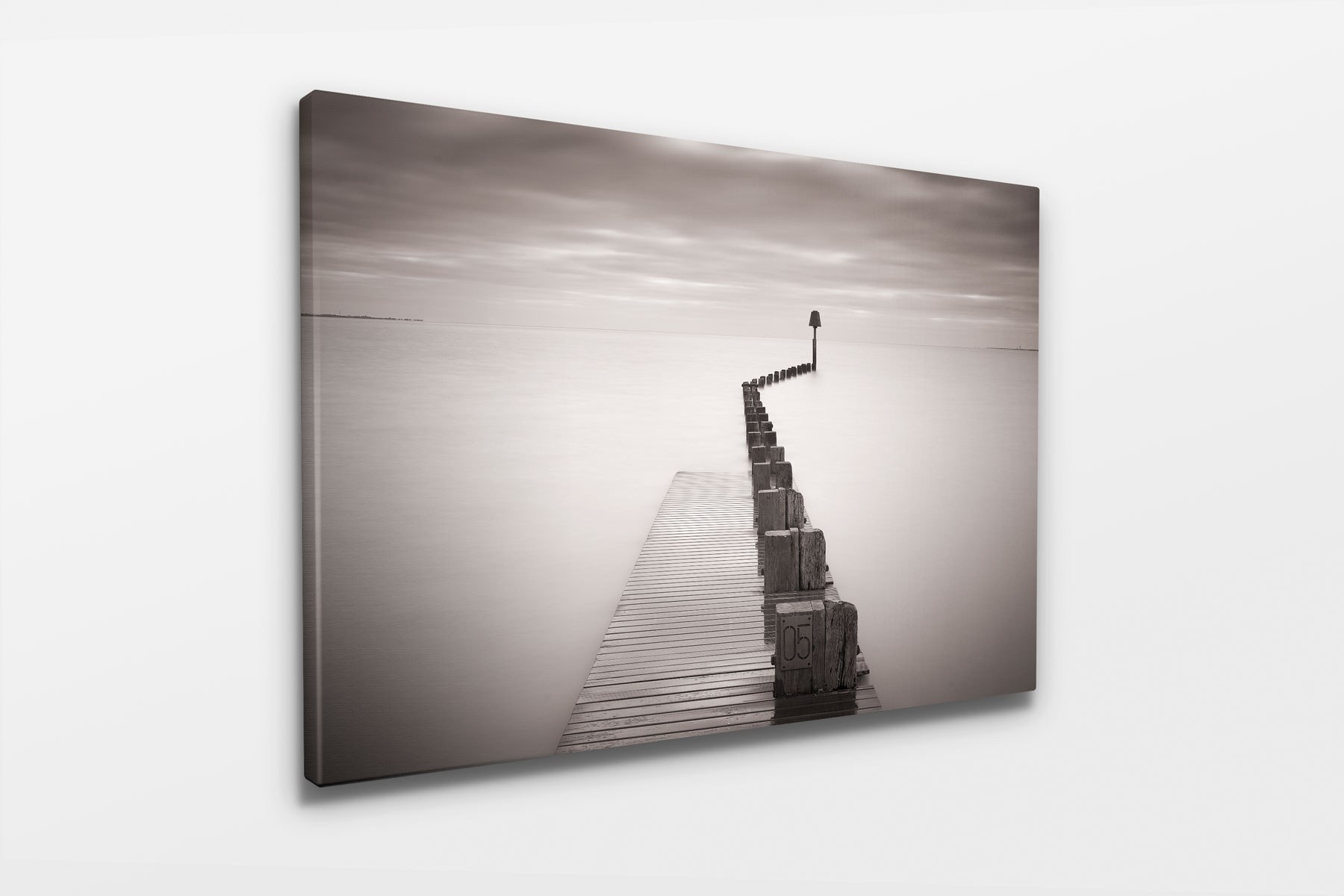 A canvas print of a long exposure photograph of a wooden pier running out into a calm sea