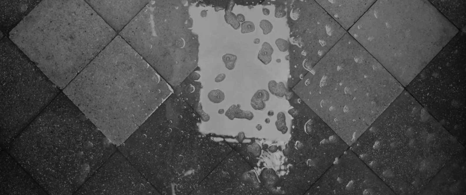 Patio tiles laid diagonally, seen from above, with soapy water and foam washing across them